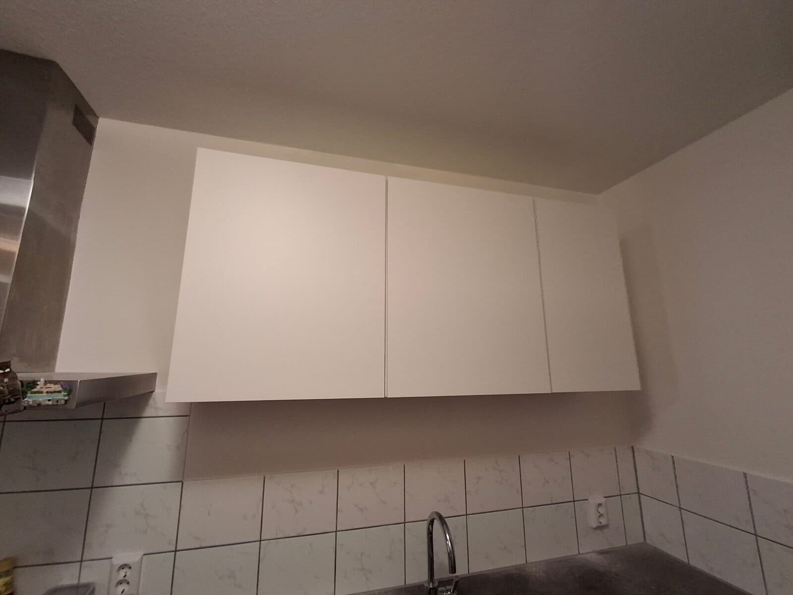 Witte hangkasten boven het aanrecht in een keuken met tegelwand