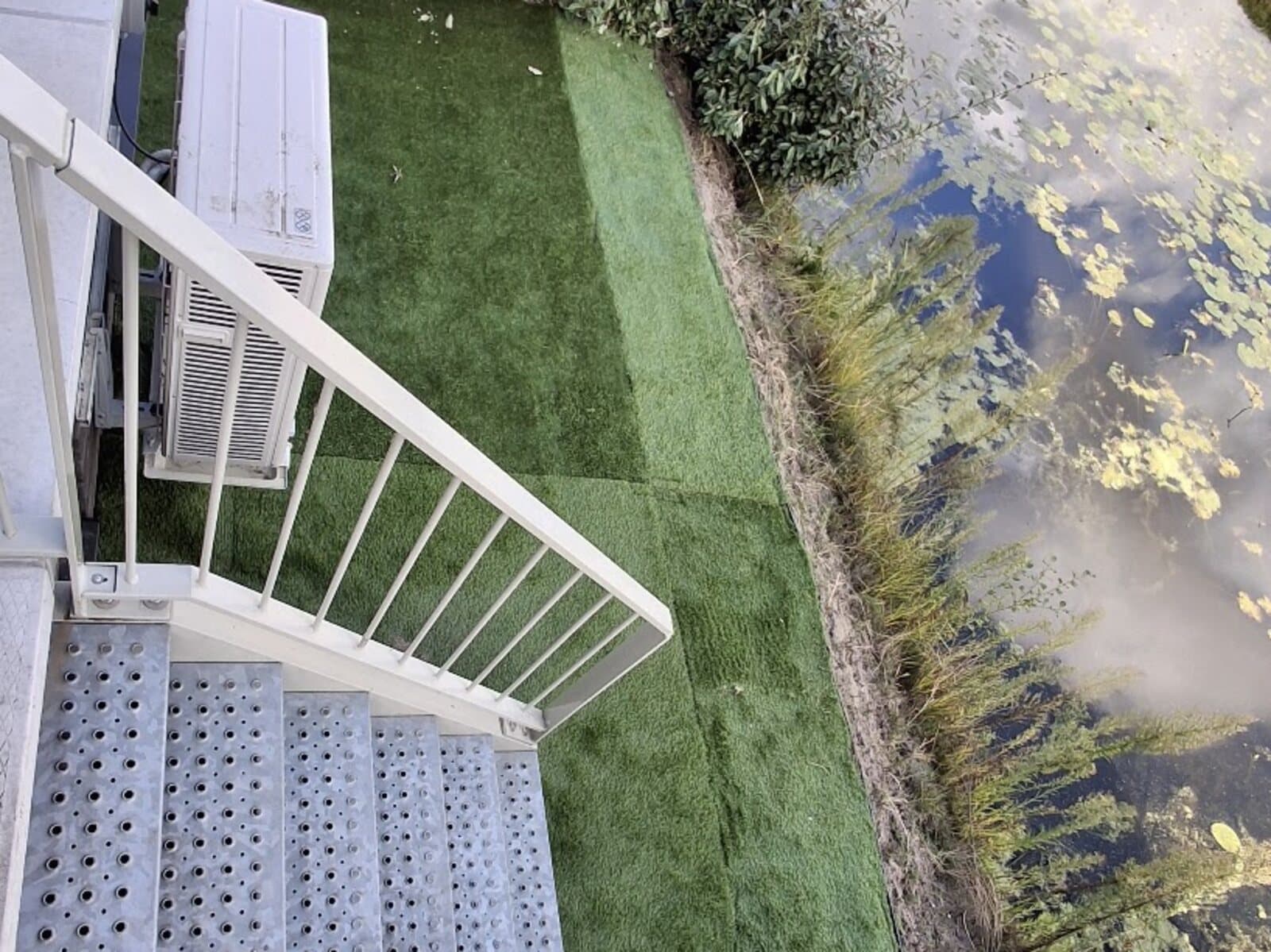 Dezelfde helling langs het water, nu bedekt met kunstgras