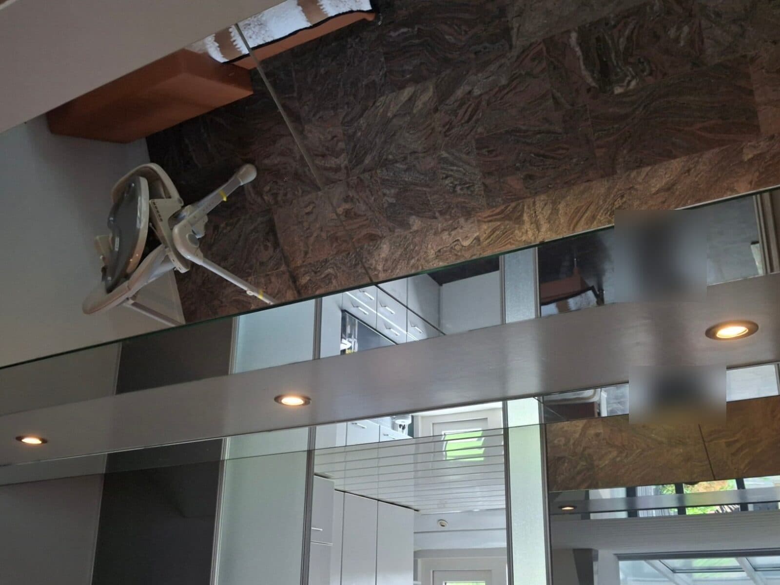 Nieuwe brandende inbouwspots in een plafondbalk boven een spiegelwand