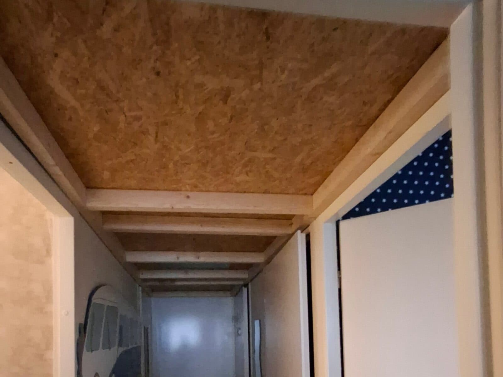 Dezelfde gang met het verlaagde plafond in aanbouw: balken en OSB-platen met opbergruimte erboven