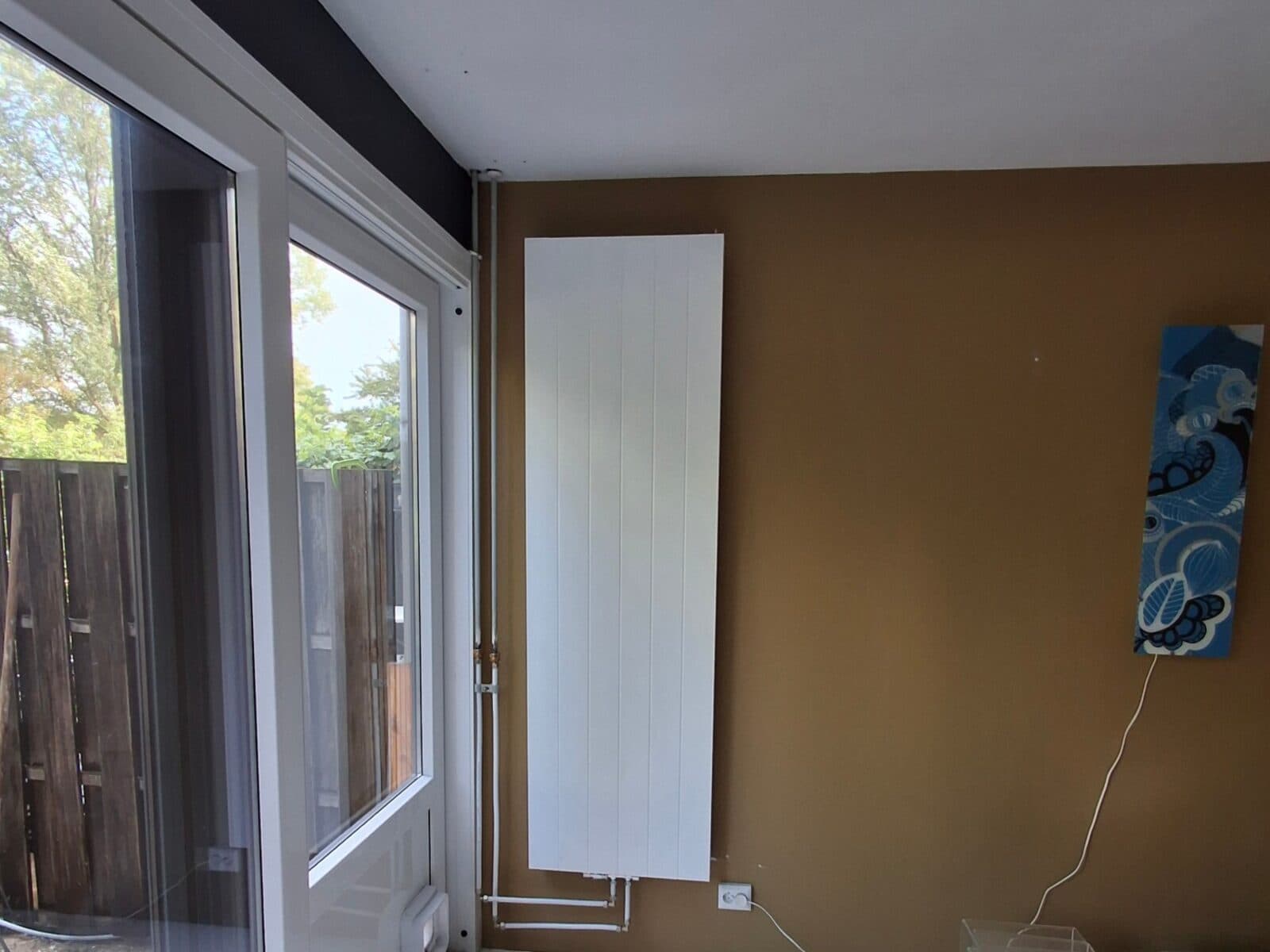 Verticale radiator aan de muur, met het stopcontact op de nieuwe, lagere plek