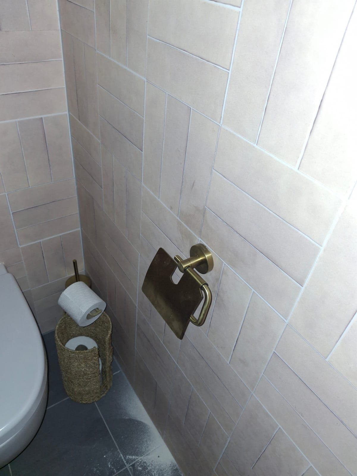 Klein toilet met roze tegels, messing kraan en handdoek