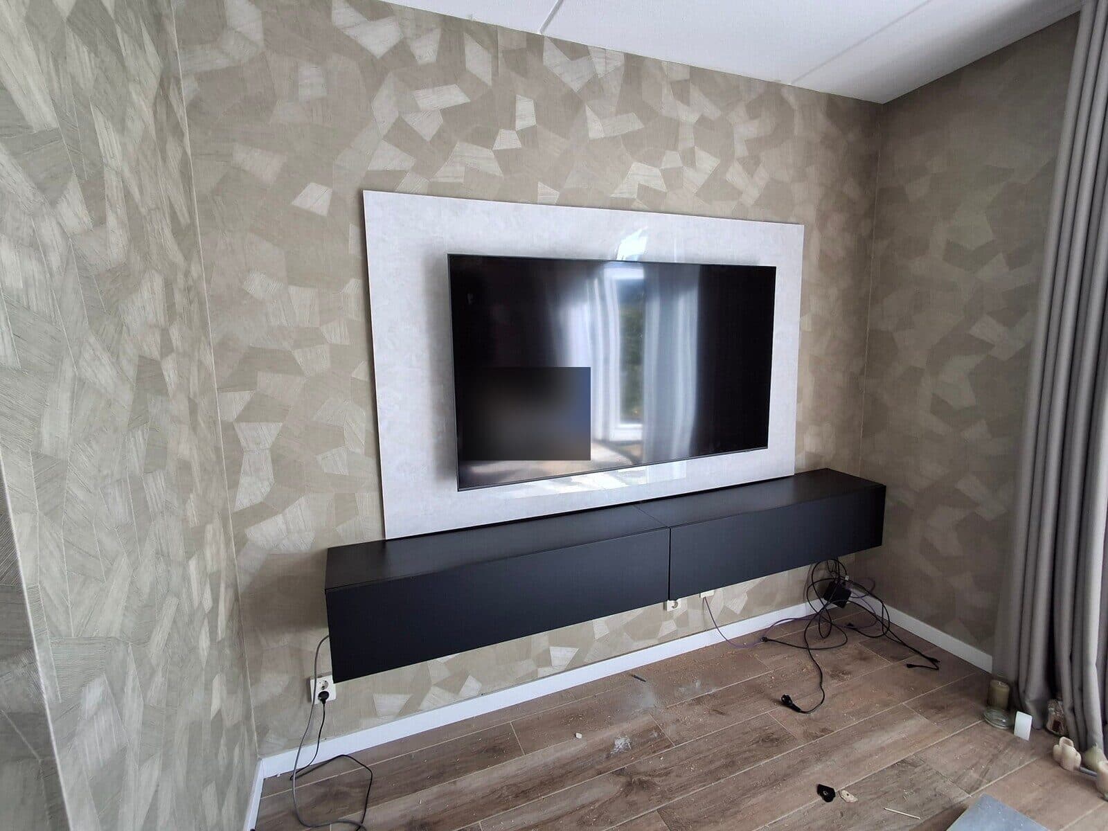 Lichte tv-achterwand met een televisie en een zwevend zwart tv-meubel op maat
